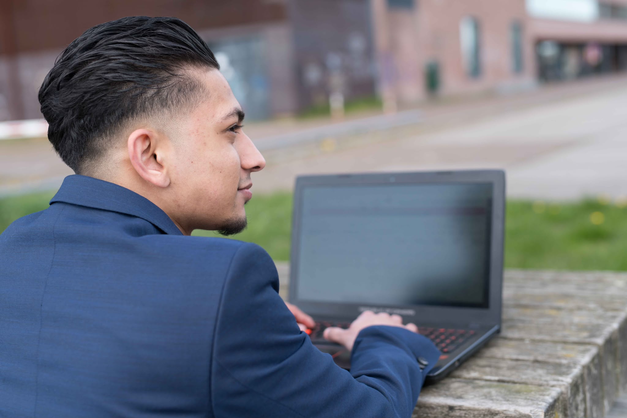 Jason Mohab-Ali werkt buiten aan zijn laptop.